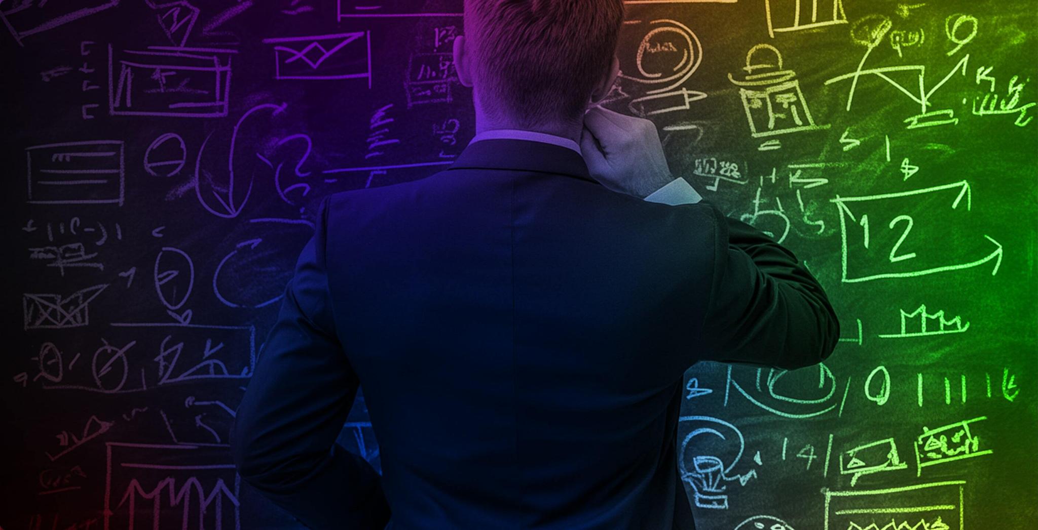 Man in a suit facing a chalkboard covered in business diagrams and charts