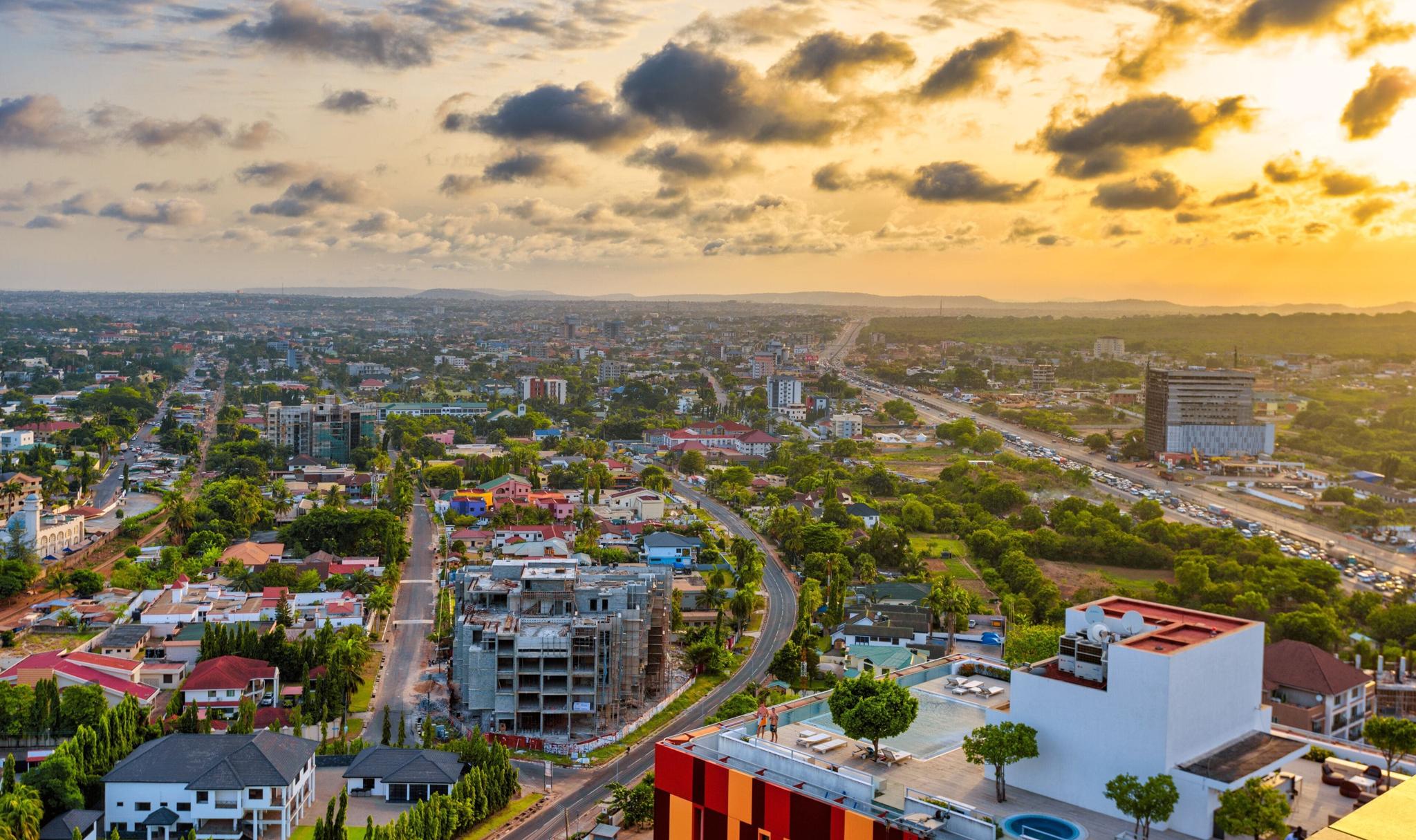 Aerial view of Accra at sunset with low-rise buildings and roads