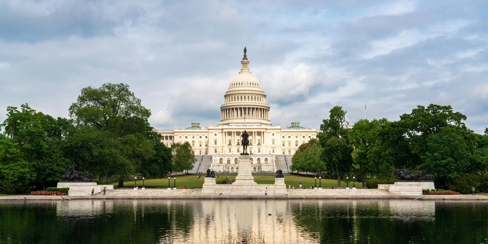 U.S. Capitol building reflected in a pond under a cloudy sky