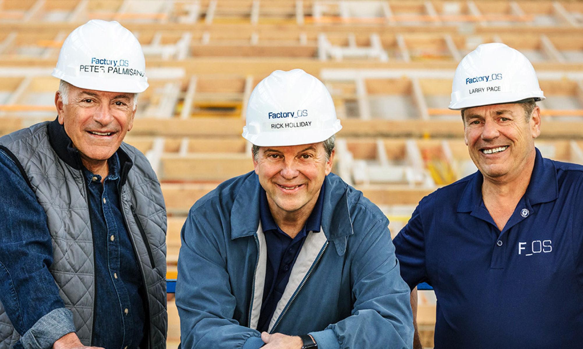 Three Factory OS staff in branded hard hats smiling at a timber frame factory