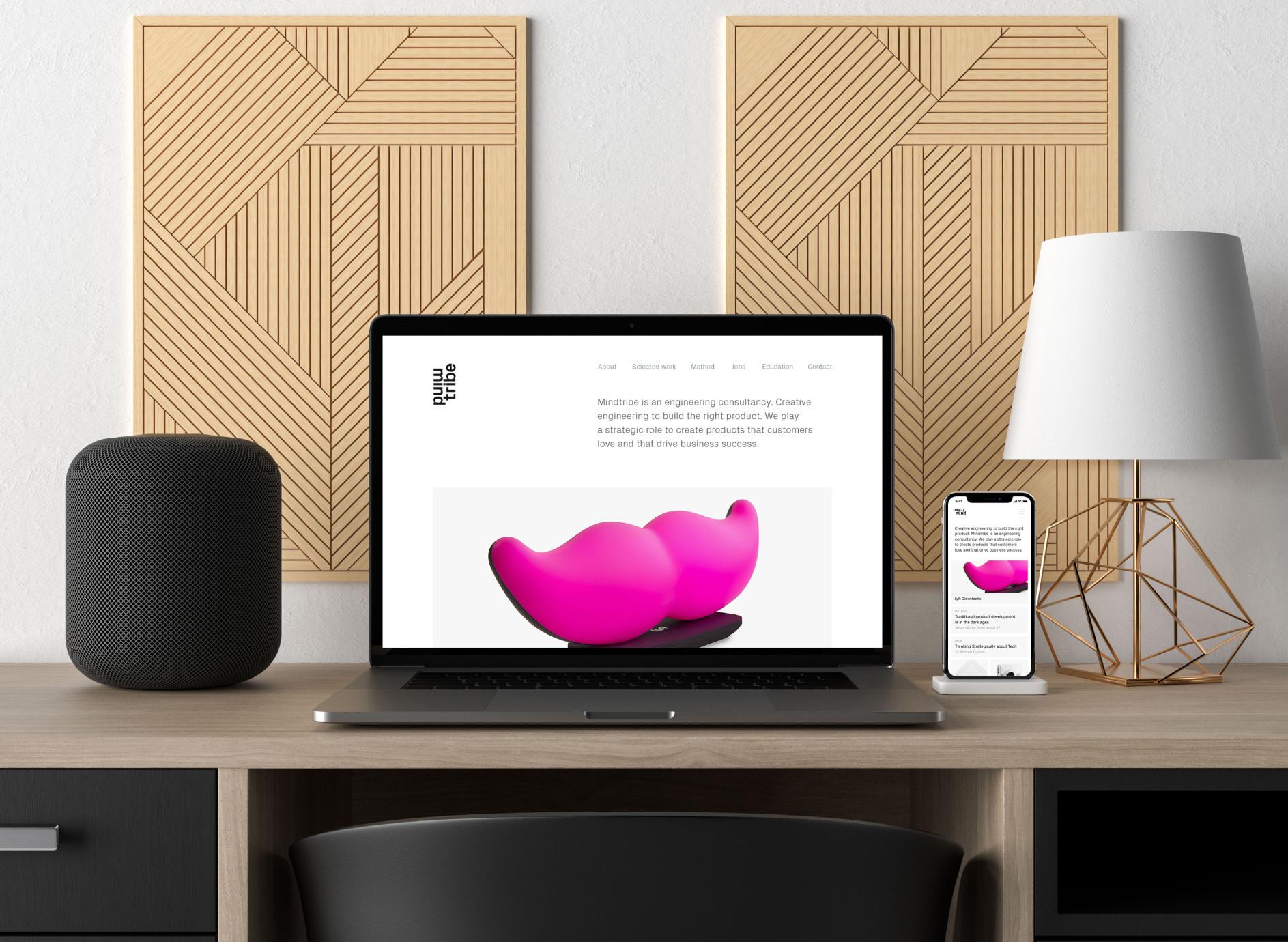 Laptop and phone on a styled desk showing the MindTribe engineering consultancy site