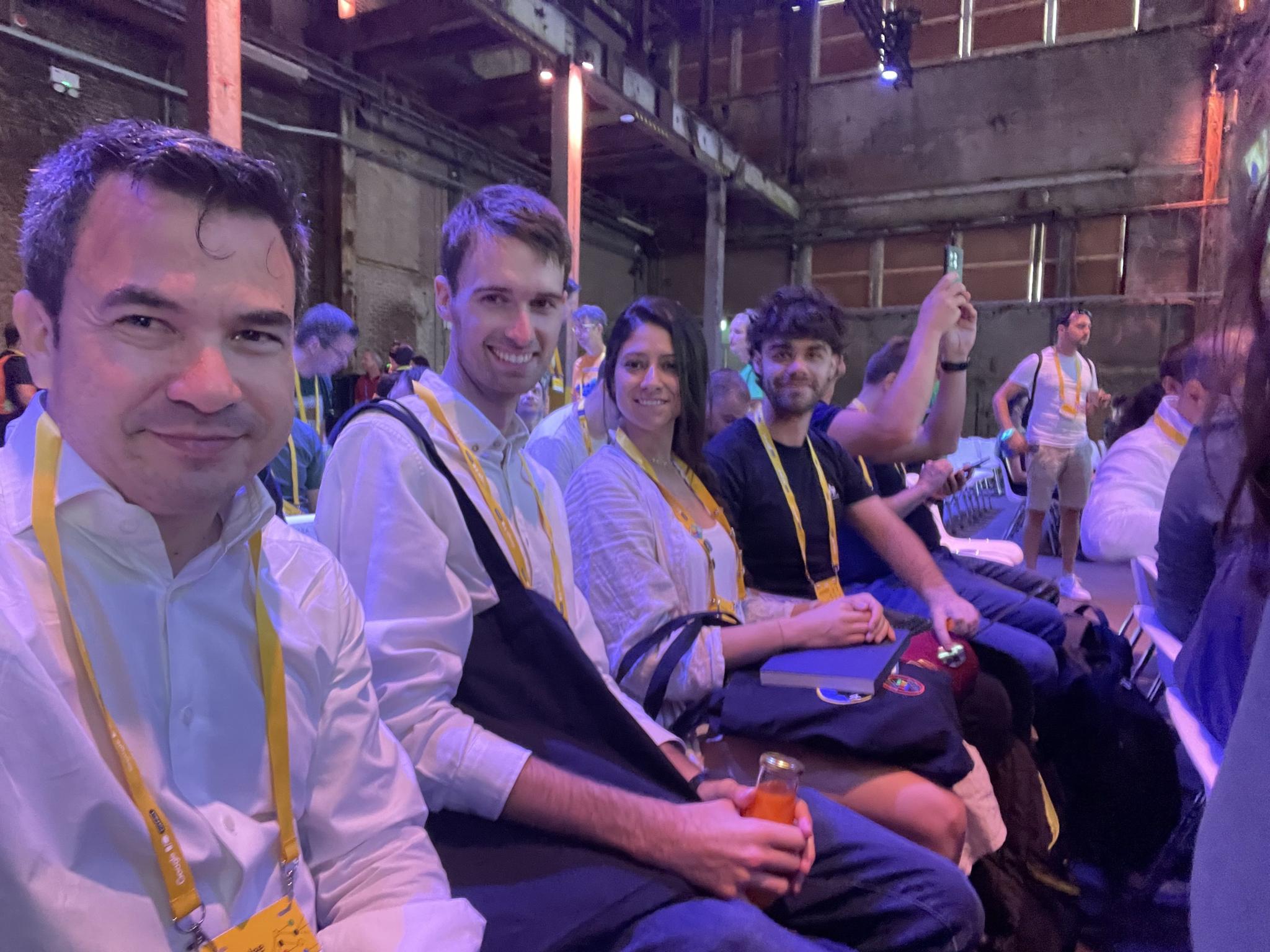 Conference attendees seated in a row wearing yellow lanyards