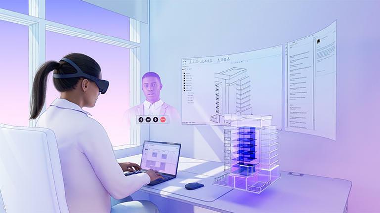 Person using augmented reality headset and laptop to review a holographic building model and virtual screens