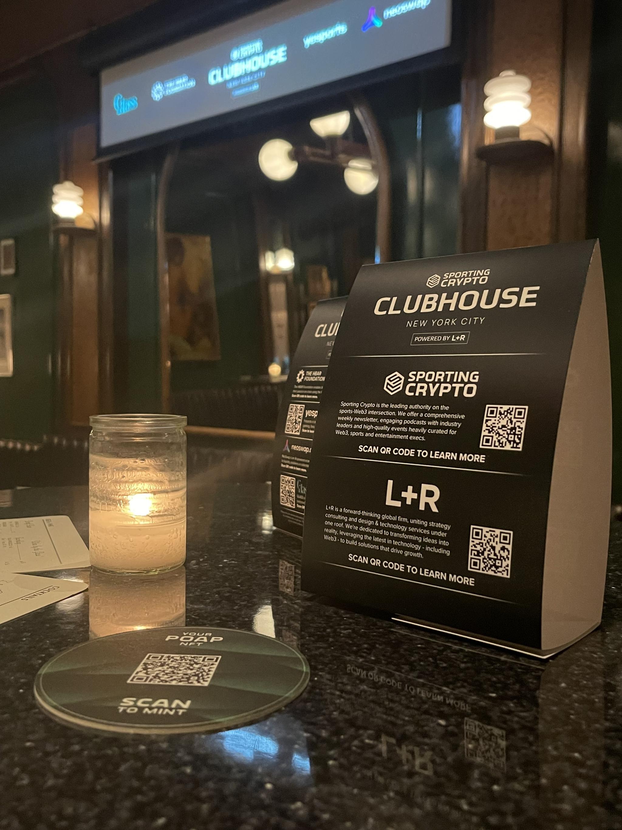 Sporting Crypto Clubhouse table signs with QR codes beside a candle