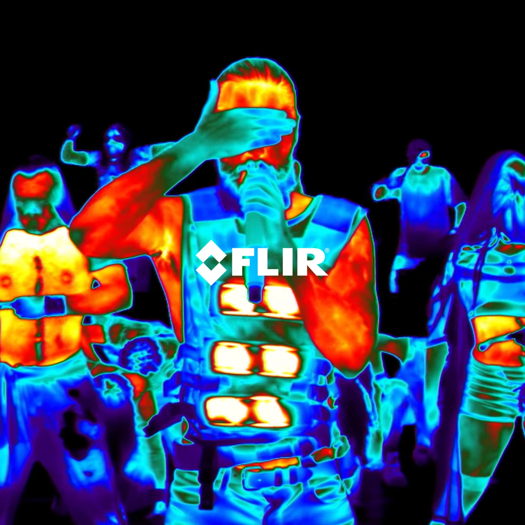 Thermal camera view of a performer singing into a microphone amid a crowd, with FLIR logo overlaid
