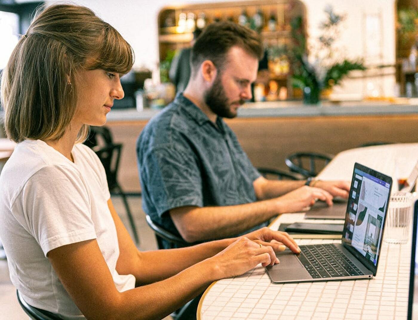 Two people working on laptops at a cafe table