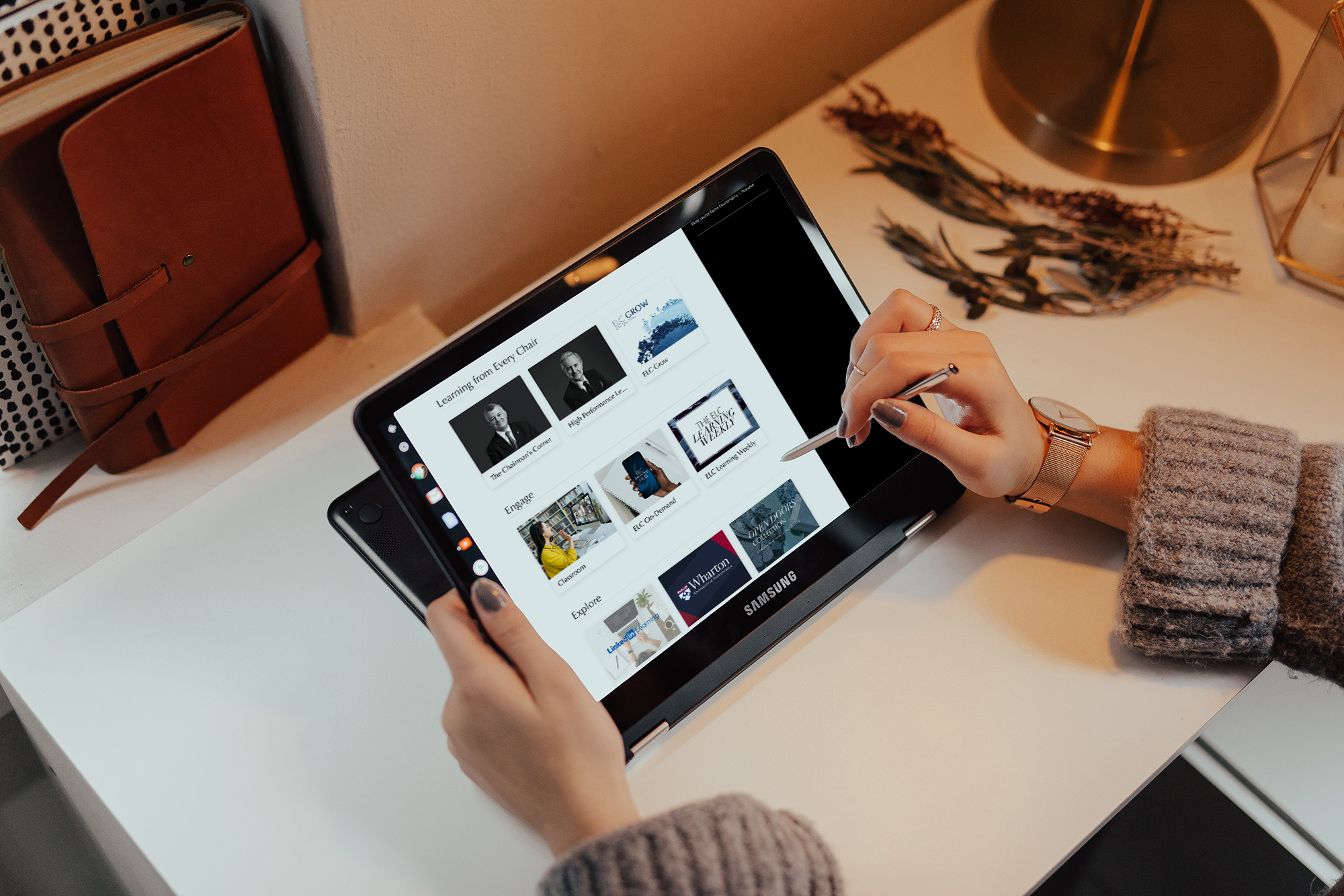 Person using a tablet showing learning modules on a desk