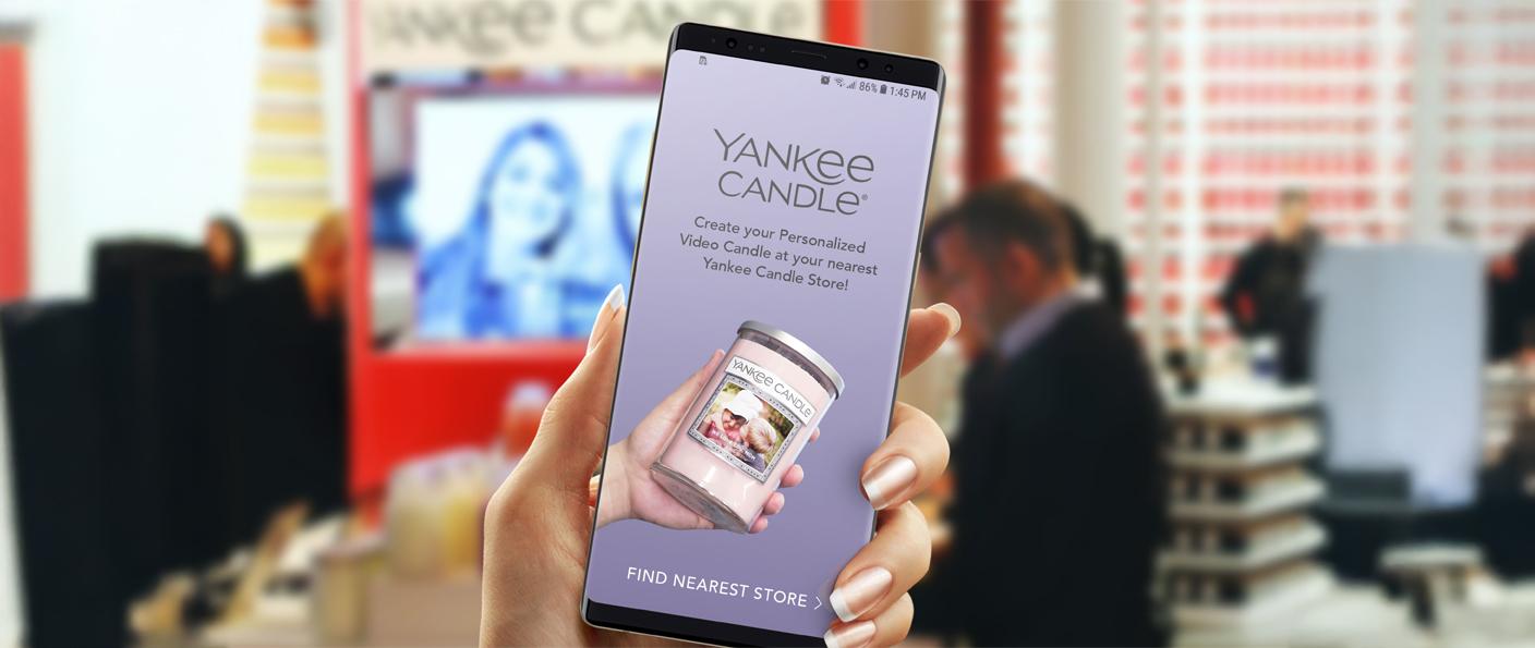 Phone showing the Yankee Candle personalised video candle app inside a Yankee Candle store