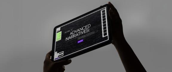 WB Adv Narratives Desktop Cover Hands hold a tablet showing an Advanced Narratives interface.