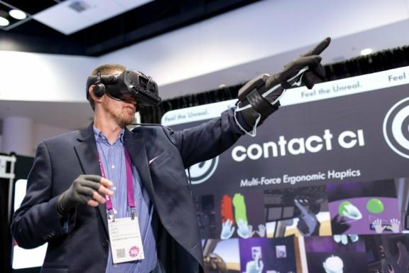 Person wearing a VR headset and haptic gloves at a Contact CI booth
