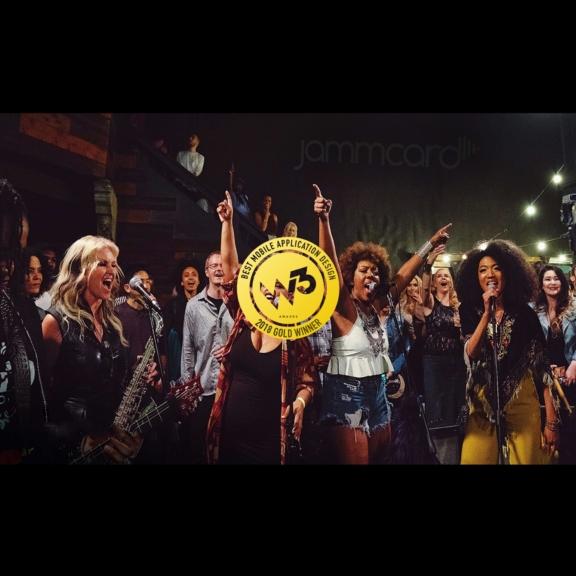 Singers on stage with a 2018 W3 Gold Winner award badge over the scene