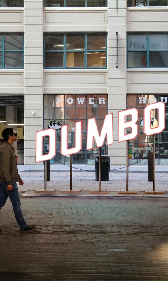 Dumbo Hero Mobile Man wearing smart glasses walks past the large DUMBO sign in Brooklyn