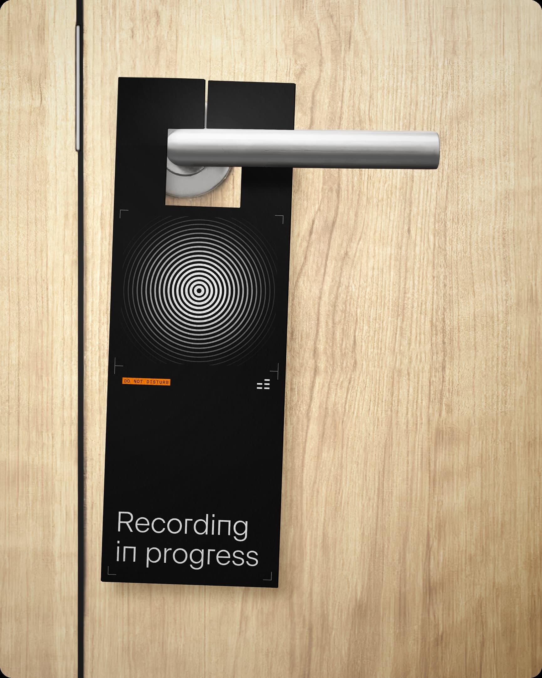Door hanger on a wood door reading "Recording in progress" with a circular sound pattern