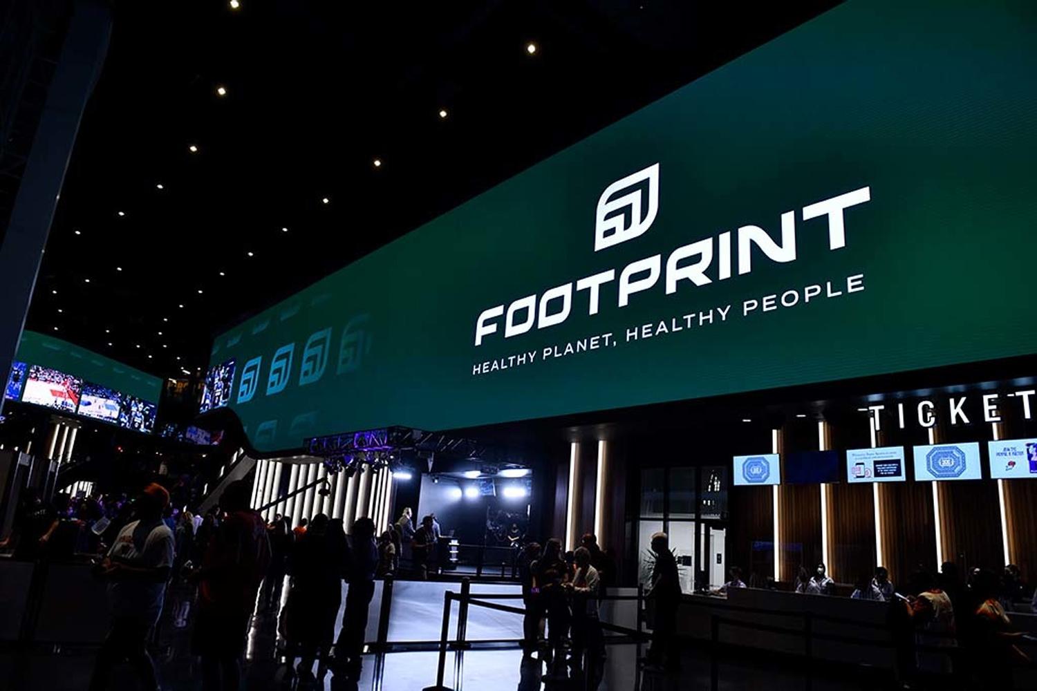 Footprint logo and slogan on a large digital display above a ticket counter in a dark venue