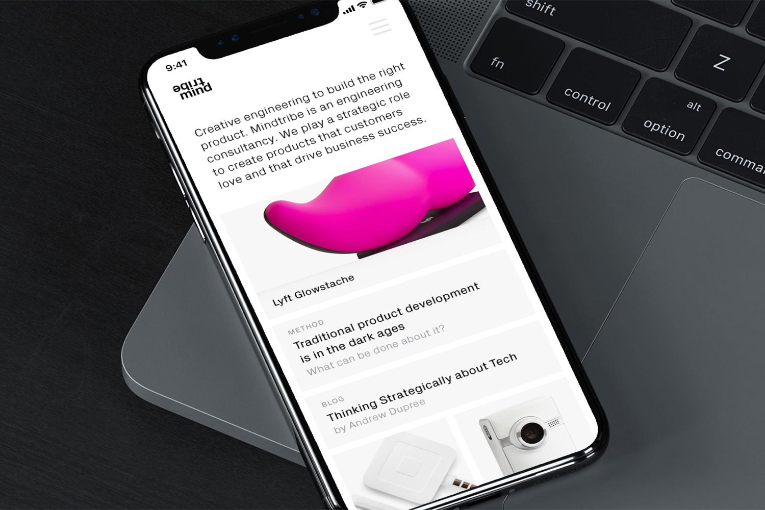 Phone resting on a laptop showing the Mindtribe mobile homepage