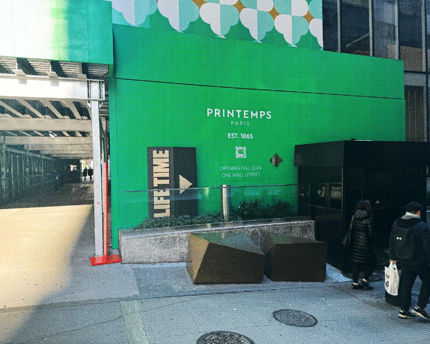 Green Printemps construction facade on a city sidewalk with pedestrians nearby.