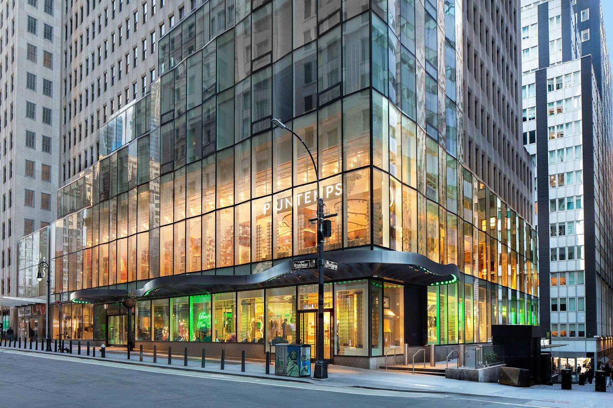 Glass Printemps storefront on a city street with green lighting visible inside.