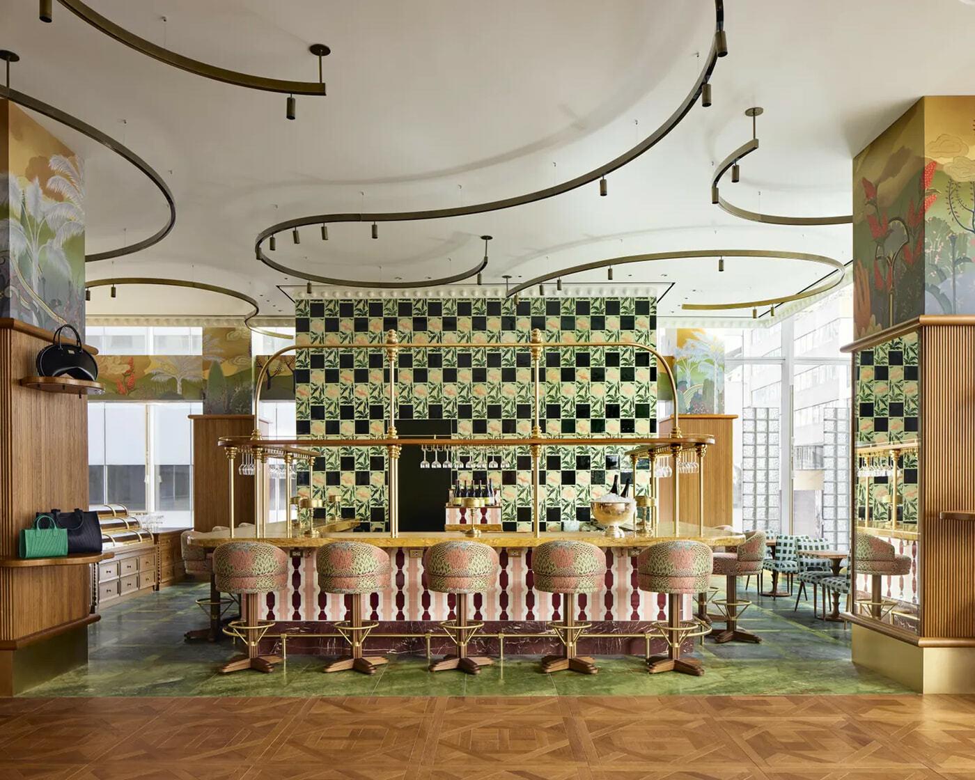 Patterned bar area with brass rails, upholstered stools, and decorative wall panels.