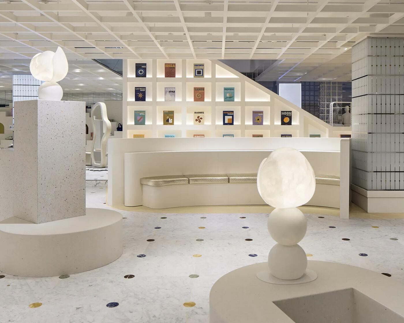 White retail lounge with illuminated sculptures, curved seating, and colorful displays on the wall.