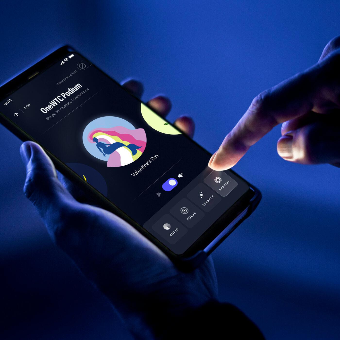 Hand tapping a phone app to pick a Valentine's Day effect for the OneWTC Podium