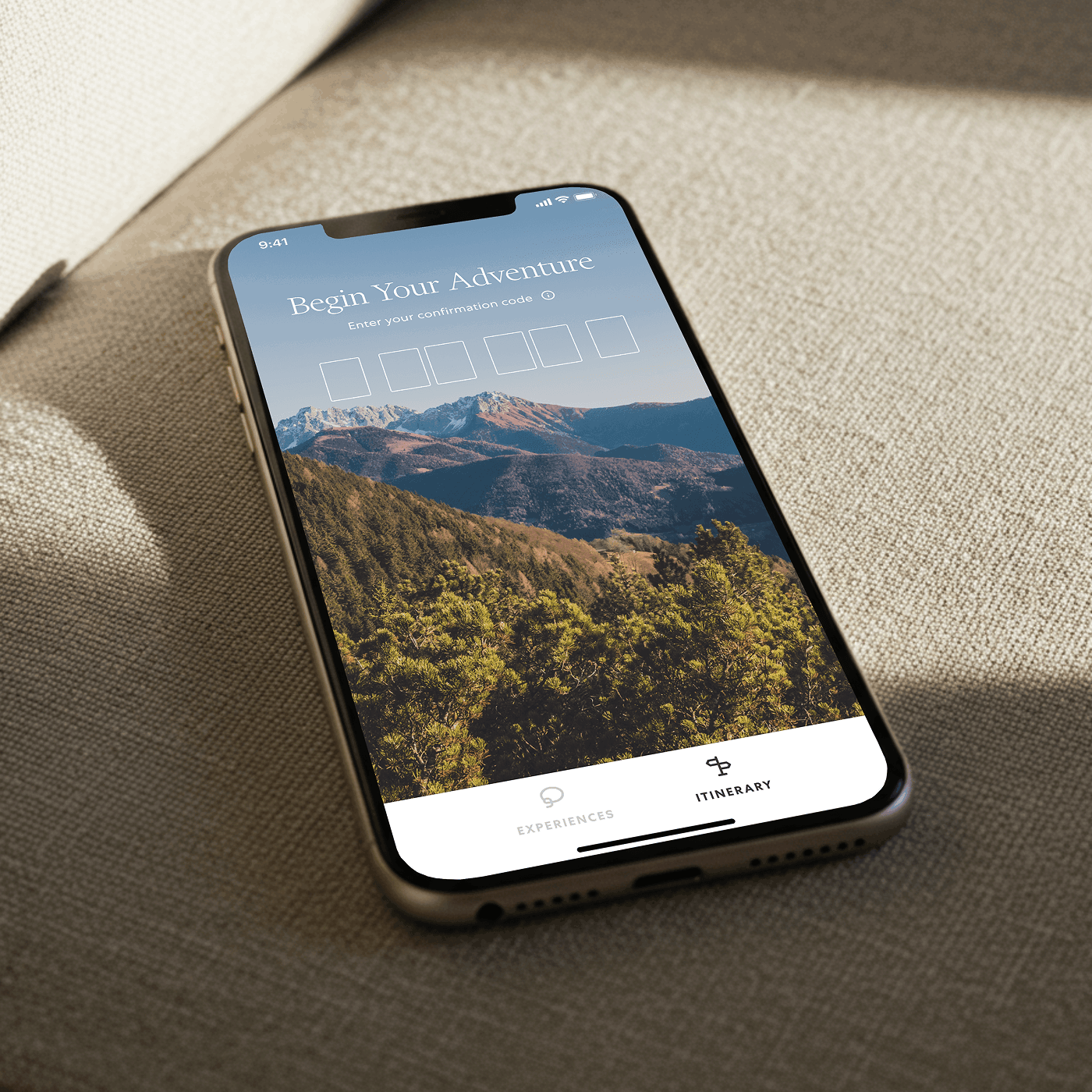 Smartphone on fabric showing the Begin Your Adventure confirmation code screen over a mountain view
