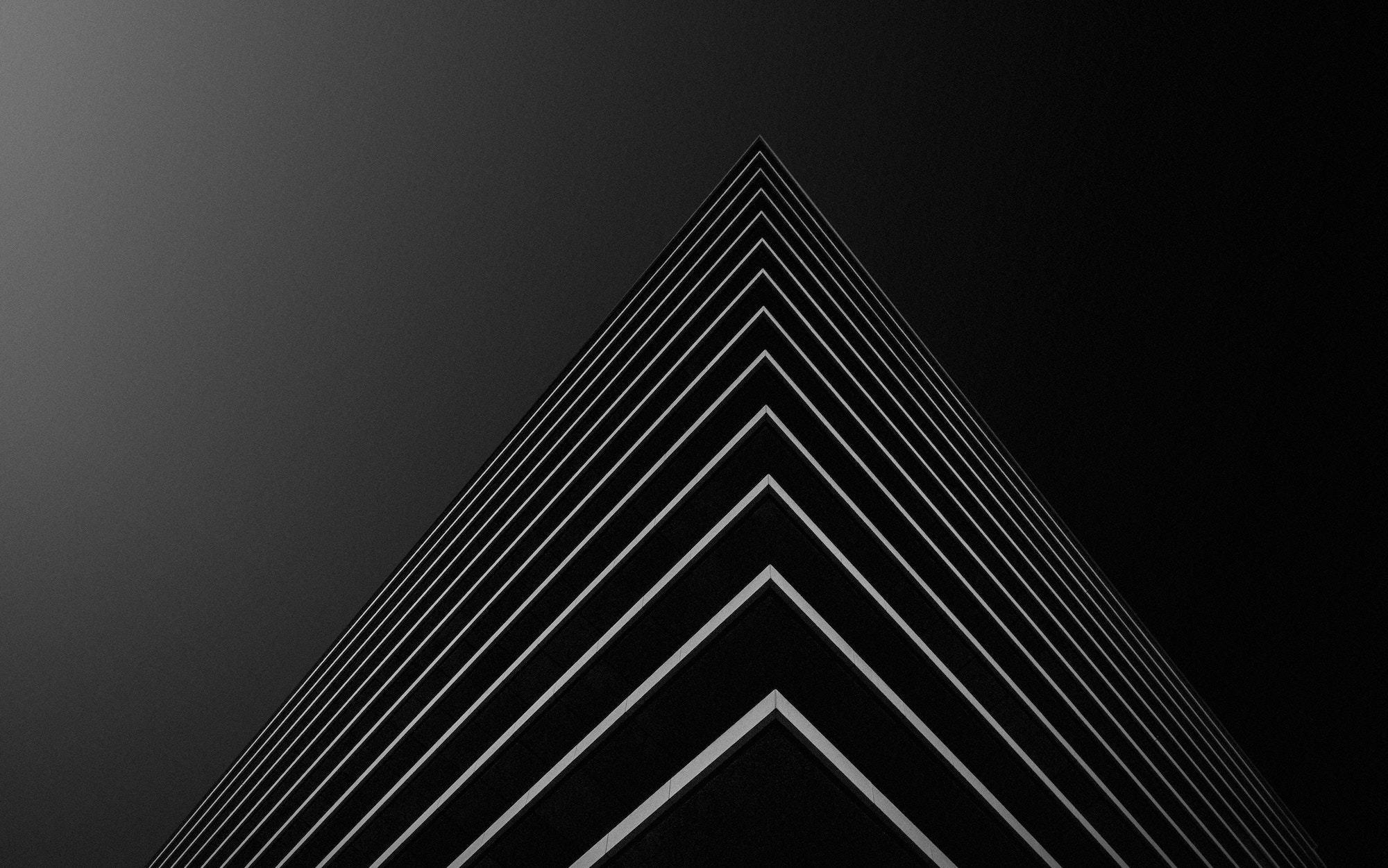 Corner of a dark modern building shot from below, its floor lines converging to a point