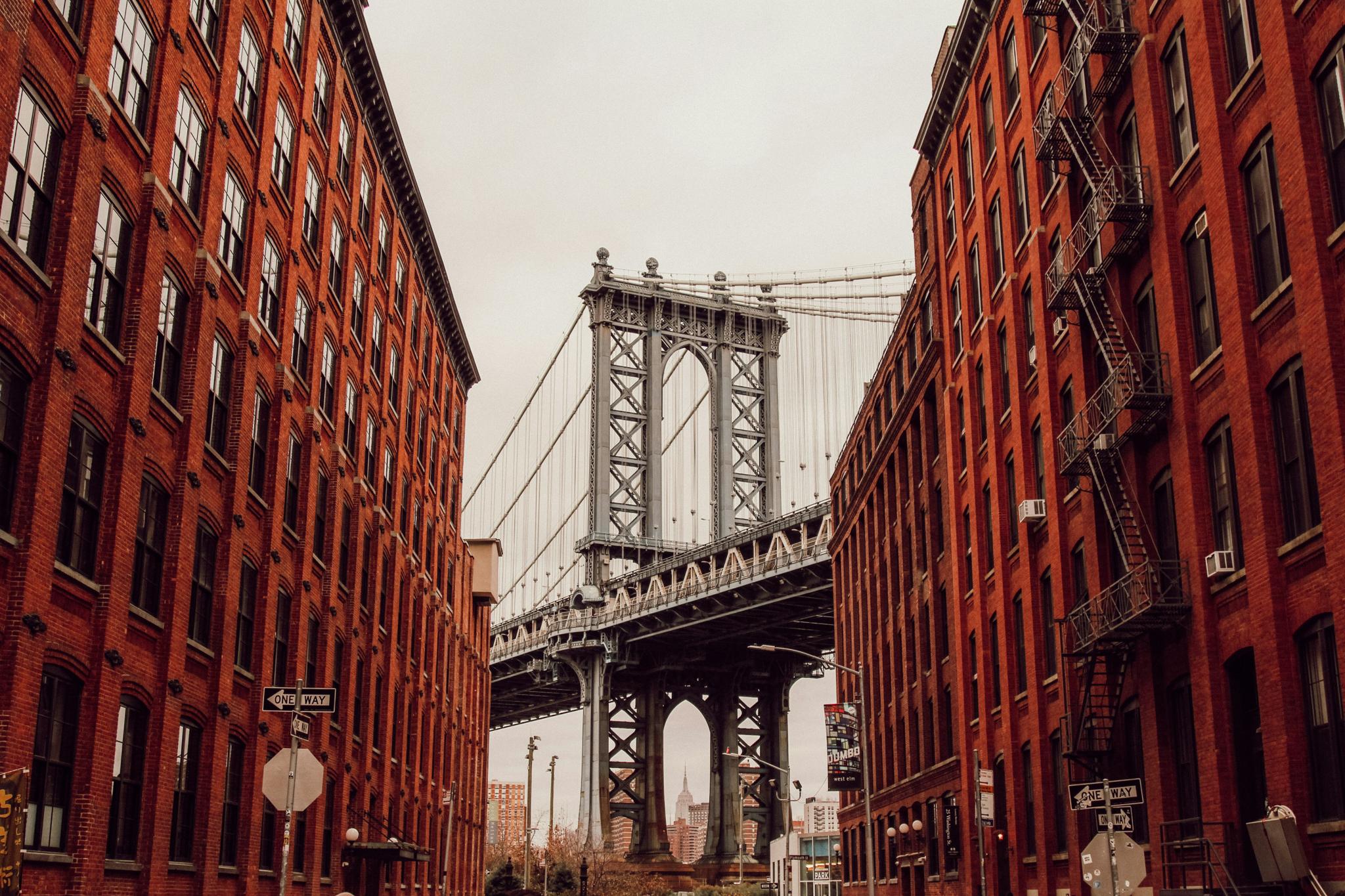 Manhattan Bridge framed by red brick buildings on a city street