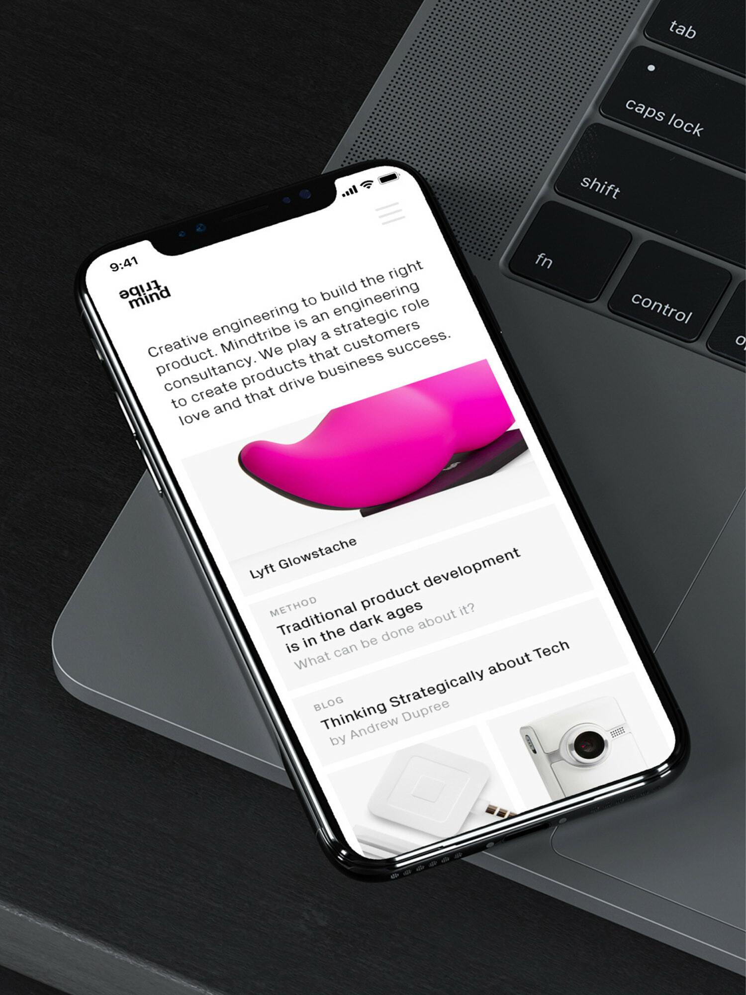 Phone resting on a laptop showing the Mindtribe mobile homepage