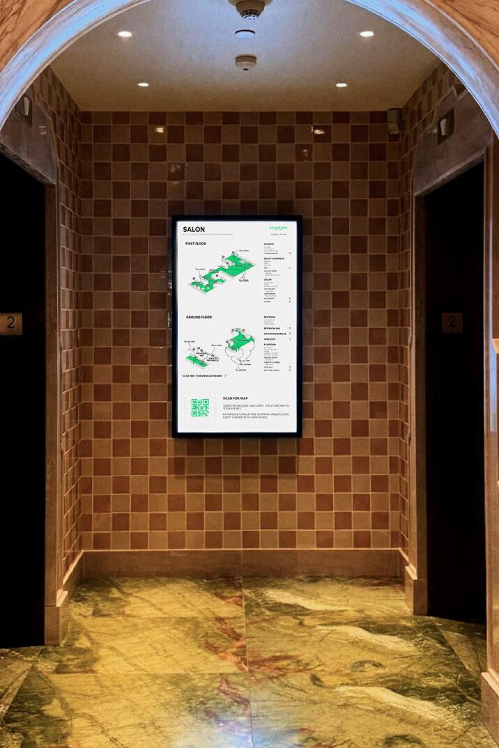 Digital Salon wayfinding map mounted between elevator doors in a tiled hallway.
