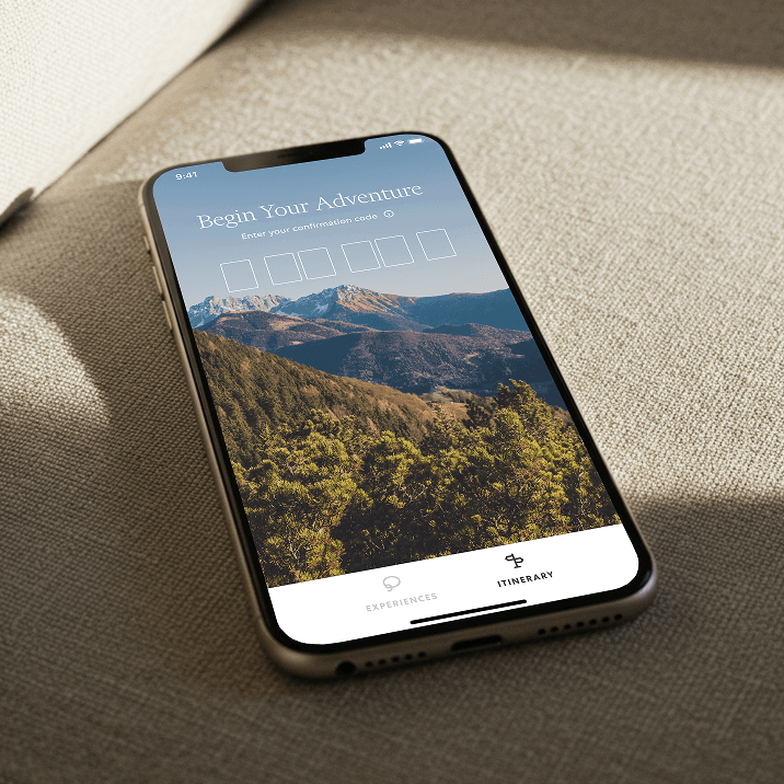 Smartphone on fabric showing the Begin Your Adventure confirmation code screen over a mountain view