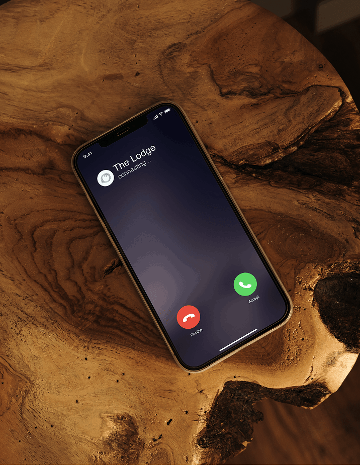 Smartphone with The Lodge incoming call beside a chair on a wood table