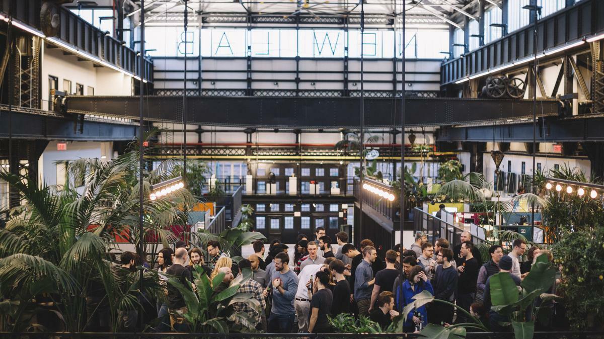 Crowd gathered under the Newlab sign in the plant-filled Brooklyn Navy Yard hall.