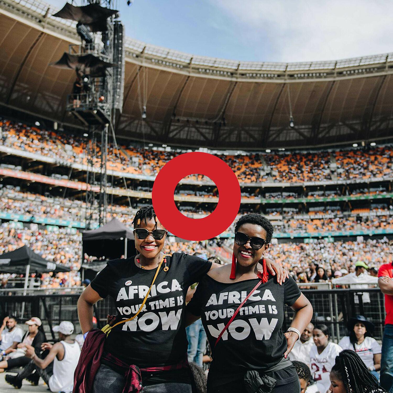Two women in Africa Your Time Is Now shirts in a crowded stadium with a red ring overlay
