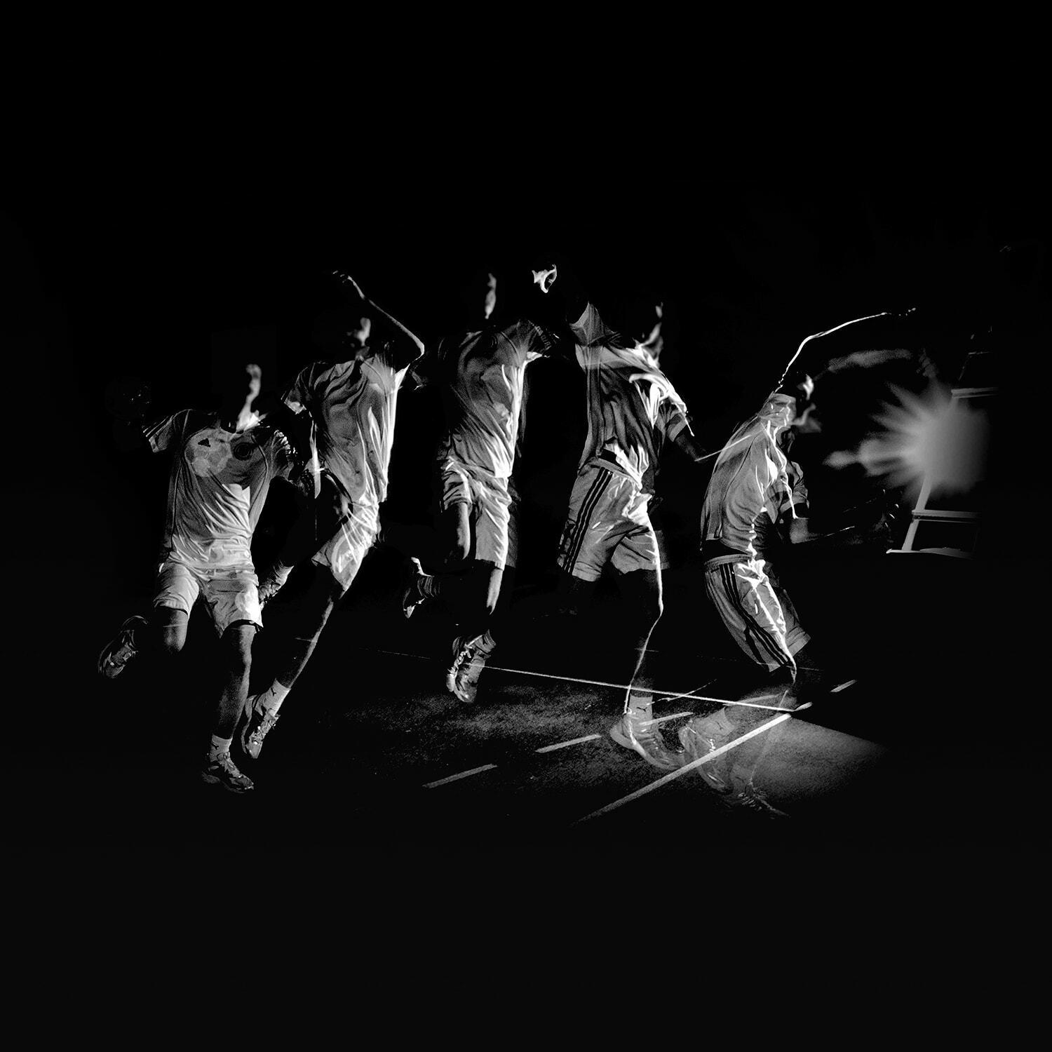 Multiple-exposure shot of an athlete leaping across a floodlit pitch at night