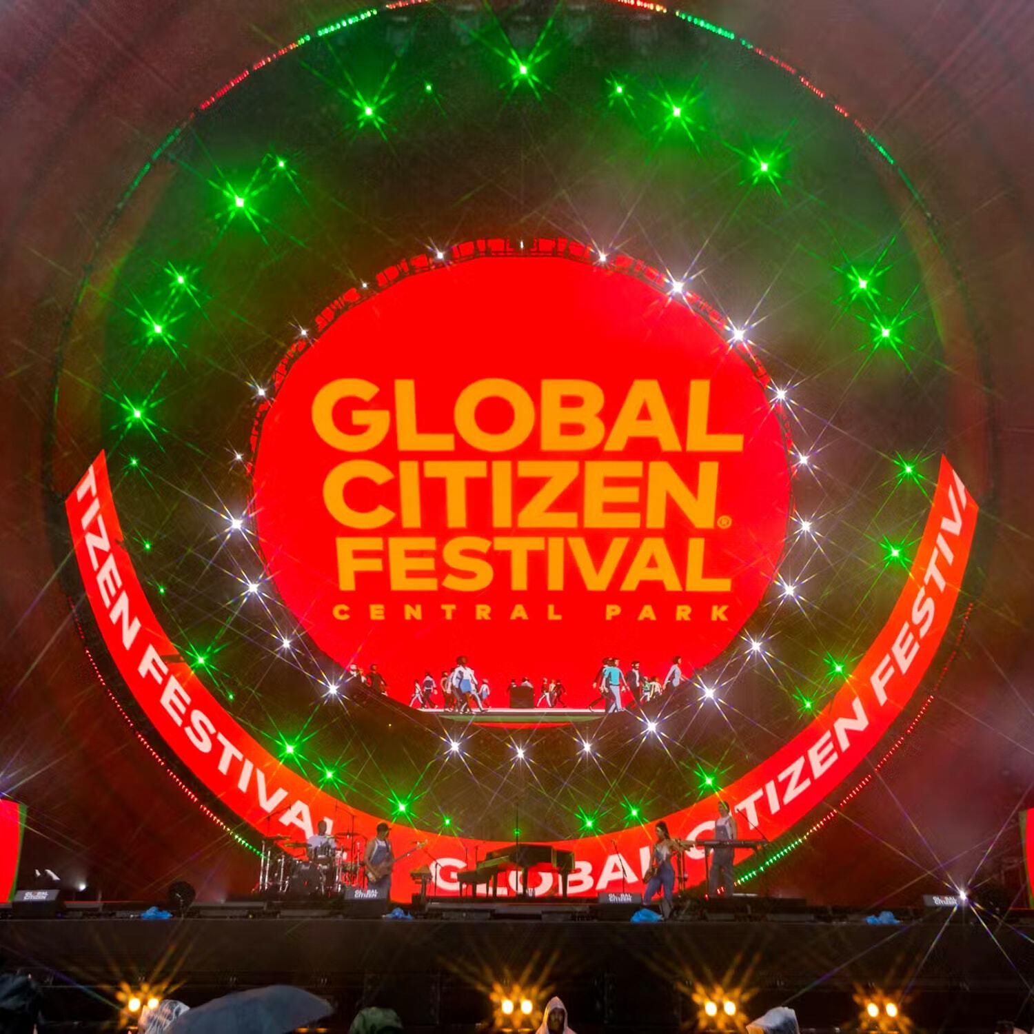 Global Citizen Festival Central Park stage, performers under a red circular screen and green lasers