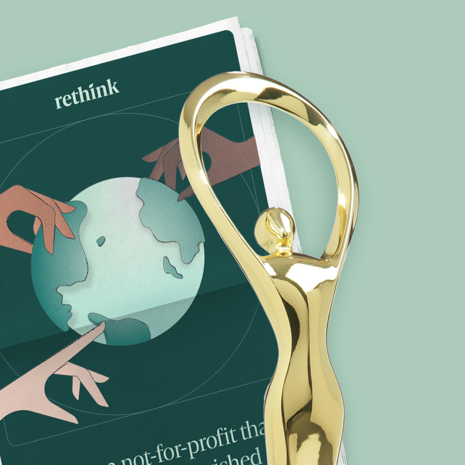 Gold trophy standing over a Rethink brochure on a pale green background
