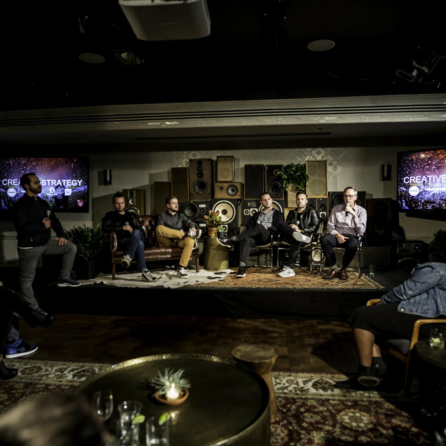Panel discussion in a dim lounge with Creative Strategy screens flanking the stage