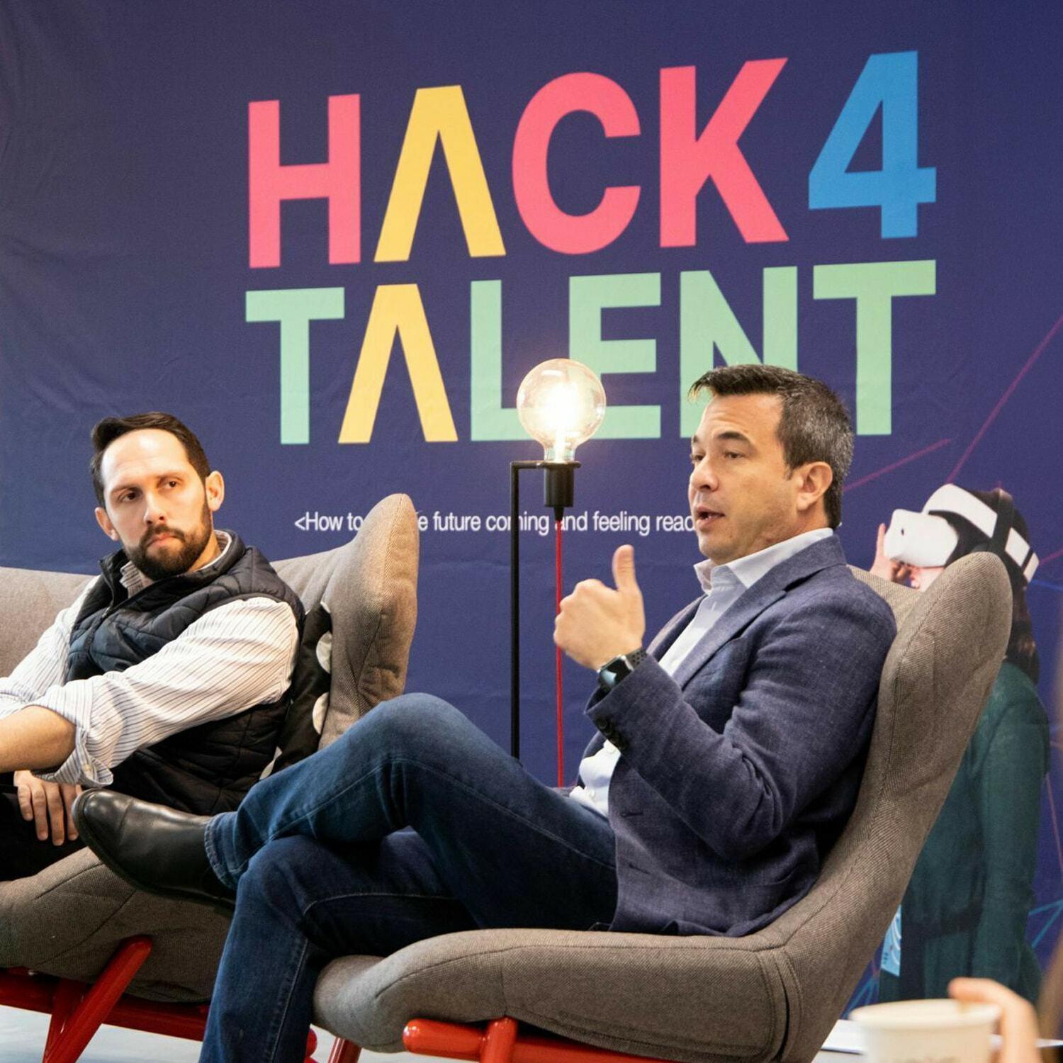 Panelists seated in armchairs in front of a Hack4Talent backdrop.
