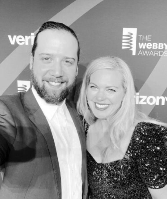 Image from i OS 12 1 Alex Levin in a suit and a woman in a sequinned dress smiling in front of a Webby Awards and Verizon backdrop